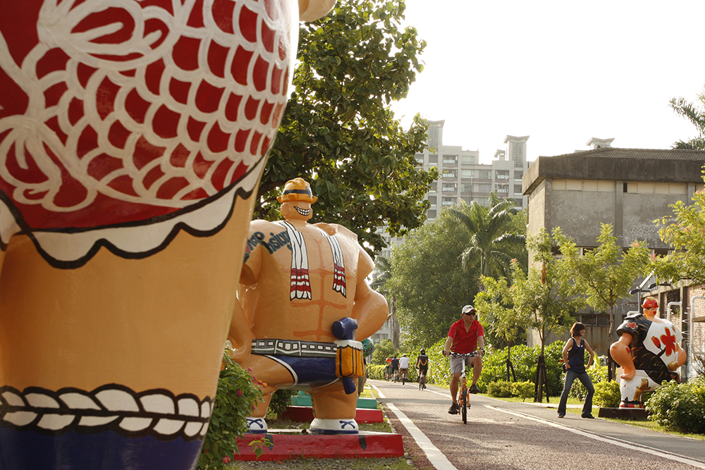 A bicyclist rides past large statues of Pier-2 Art Center in Kaohsiung