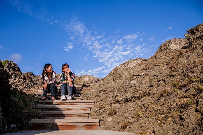 Two girls sitting on wooden steps chatting in Longkeng Ecological Protection Area
