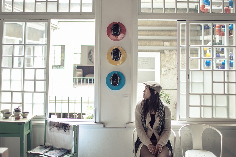 Girl sitting inside B.B. Art in front of bright windows looking to the right