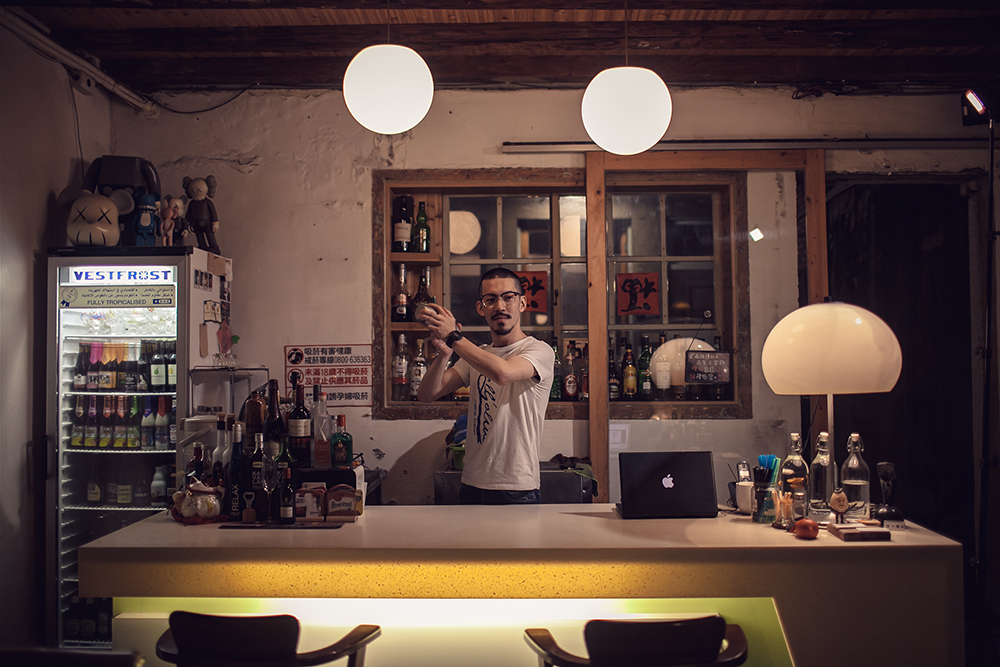 Bar tender of Taikoo standing behind bar shaking a drink