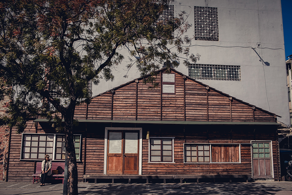 Girl sitting on bench in front of old wooden house on Hai'an Road