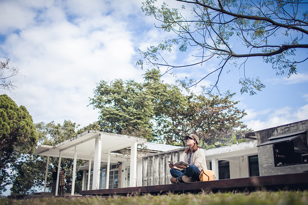 Girl sitting on the floor in front of Bywood looking into the distance