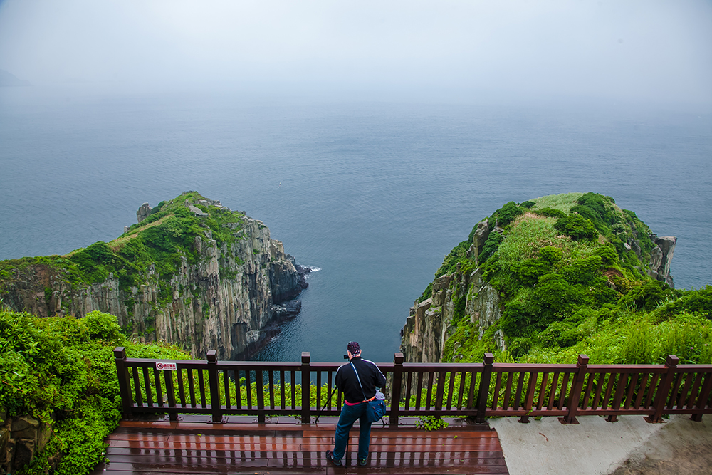 Guy taking pictures of green cliffs at Stronghold No. 33 on Dongyin Island