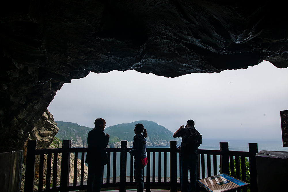 Three persons standing at the one end of Andong Tunnel looking out to the sea