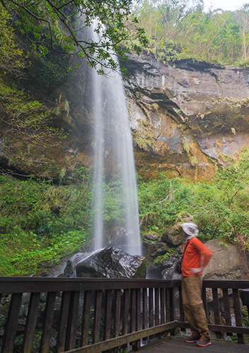 Hiker standing on wooden platform looking at Motian Waterfall