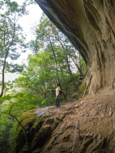 Hiker standing under the protruding wall of Pipa Cave